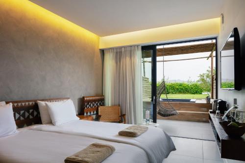 a hotel room with a bed and a large window at La Mer Resort Spa Crete in Georgioupolis