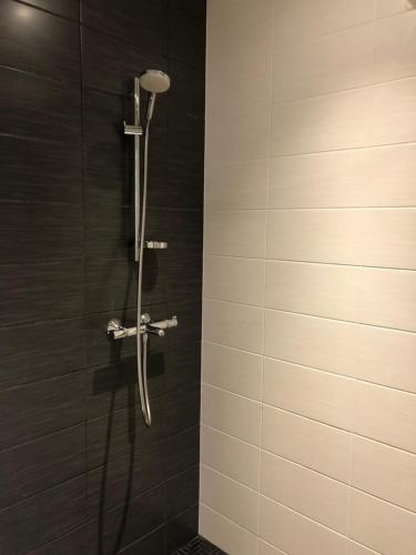 y baño con ducha y azulejos negros. en Cozy and peaceful apartment, en Espoo