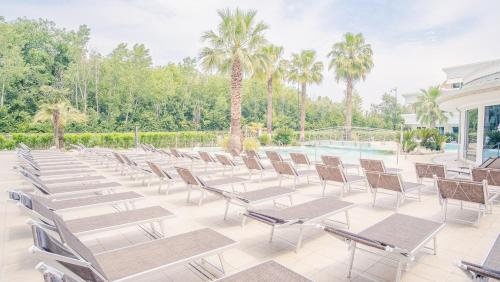 a row of chairs and a pool with palm trees at Relais du Lac Village - Italian Homing in Desenzano del Garda