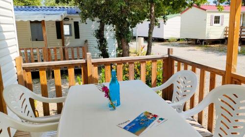Camping Rives du Lac de Sainte Croix في بودوان: طاولة بيضاء وكراسي على سطح السفينة