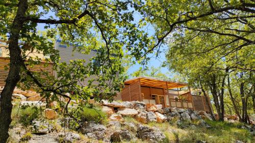 a house in the woods with a stone wall at Camping Rives du Lac de Sainte Croix in Bauduen