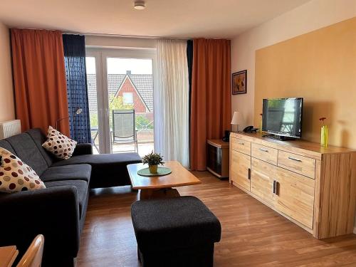 uma sala de estar com um sofá e uma televisão em Haus am Mühlenpark Whg. 4 em Cuxhaven