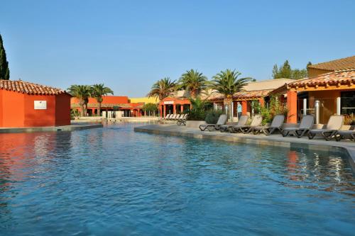 una piscina con sedie a sdraio in un resort di SOWELL RESIDENCES Les Hameaux de Camargue a Arles