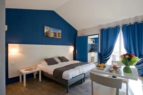 een slaapkamer met blauwe muren en een bed en een bureau bij SOWELL RESIDENCES Les Hameaux de Camargue in Arles