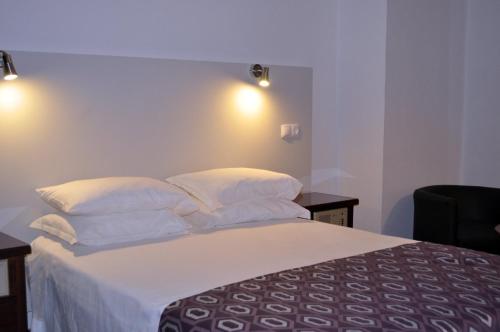 a bedroom with a bed with white sheets and pillows at Hotel Brasa in Elvas