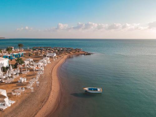 a beach with chairs and a boat in the water at Lemon & Soul Makadi Garden in Hurghada