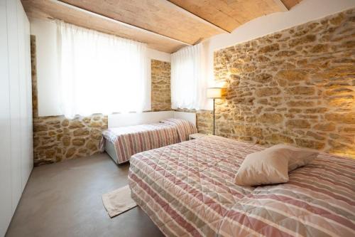 a bedroom with two beds and a stone wall at Appartamento il Poggino in Colle di Val d'Elsa