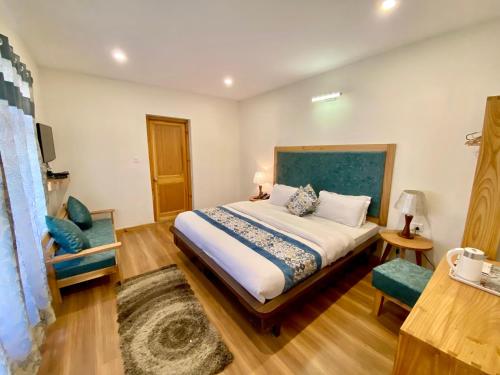 a bedroom with a large bed and a chair at Hotel Palam Hills in Leh