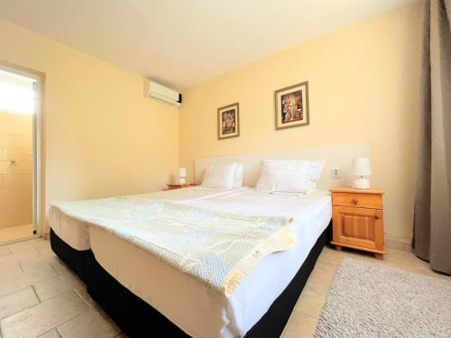 1 dormitorio con 1 cama blanca grande y mesita de noche en Lotus Family Hotel - Free Parking en Sunny Beach