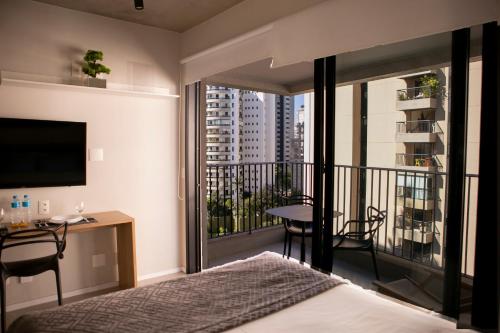 a bedroom with a bed and a balcony with a desk at Studio 31 m2 com Terraço Parque Ibirapuera Itaim Bibi in Sao Paulo
