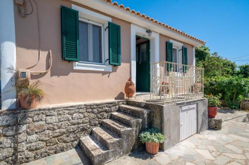 a house with green shutters and a stone wall at Pitoros Summer Cottage Kefalonia in Mesovoúnia