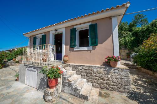 a house with a stone wall and green shutters at Pitoros Summer Cottage Kefalonia in Mesovoúnia