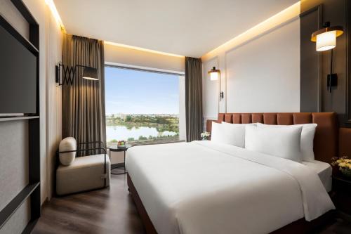 a bedroom with a large white bed and a large window at Ramada Encore by Wyndham Indore Nipania in Indore