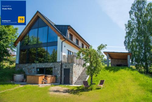 une maison sur une colline avec deux chaises dans l'établissement Chata Viola, à Dolní Morava