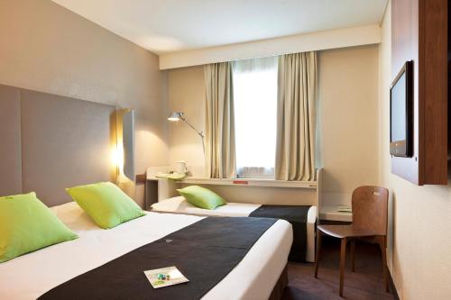 ボレーヌにあるCampanile Bollène A7のベッド2台と窓が備わるホテルルームです。