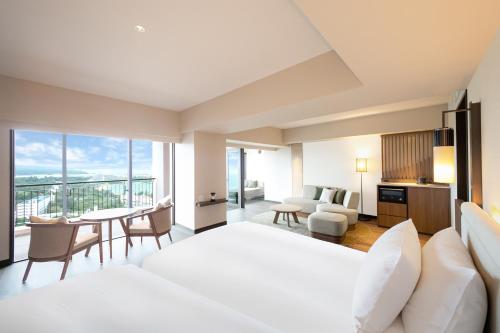 a hotel room with a large bed and a table and chairs at Oriental Hotel Okinawa Resort & Spa in Nago