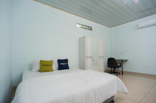 Habitación blanca con cama blanca y escritorio. en Urbanview My Home Ciracas en Yakarta