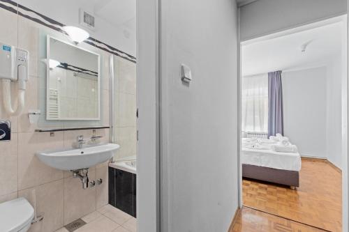 a bathroom with a sink and a toilet and a mirror at Minerva Hotel in Medulin