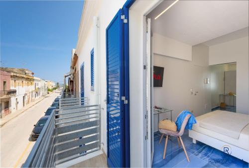 a bedroom with a bed and a balcony with a door at Rivazzurra Beach Rooms in San Vito lo Capo