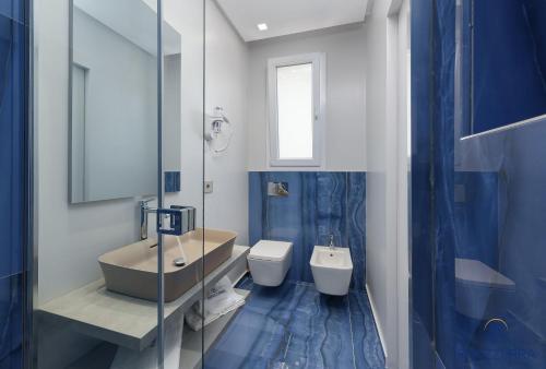 uma casa de banho azul e branca com um lavatório e um WC em Rivazzurra Beach Rooms em San Vito lo Capo