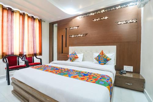 - une chambre avec un grand lit et une chaise rouge dans l'établissement FabHotel Nandgiri Palace Near Gwalior Junction Railway Station, à Gwalior