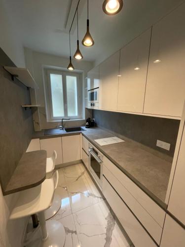 une cuisine avec des armoires blanches, une table et une fenêtre dans l'établissement Montmartre sacré cœur, à Paris