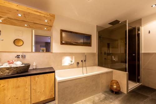 a bathroom with a tub and a shower and a sink at Mountain Chalet Kirchberg by Apartment Managers in Kirchberg in Tirol
