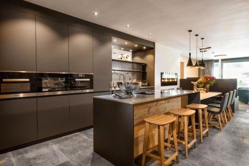 a kitchen with black cabinets and a bar with stools at Mountain Chalet Kirchberg by Apartment Managers in Kirchberg in Tirol