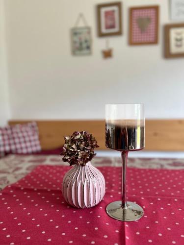 a glass of wine sitting on a table with a flower at Haus Schmetterling in Alpbach