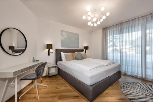 a bedroom with a bed and a desk and a mirror at Mountain Chalet Kirchberg by Apartment Managers in Kirchberg in Tirol