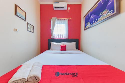 um quarto com uma parede vermelha e uma cama. em RedDoorz Syariah at Sudirman Street Garut em Garut