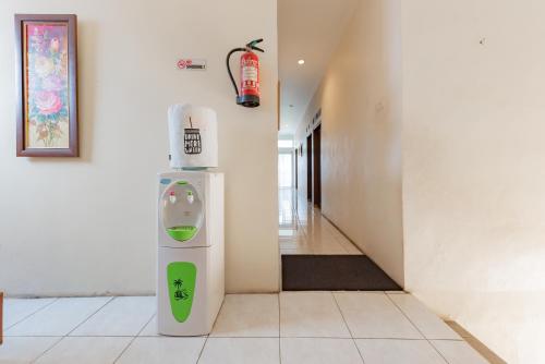 a refrigerator in a hallway with a fire extinguisher on the wall at RedDoorz Syariah at Sudirman Street Garut in Garut