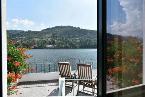 a balcony with two chairs and a view of a lake at Feel Discovery Casa do Rio Douro Valley in Riba Douro