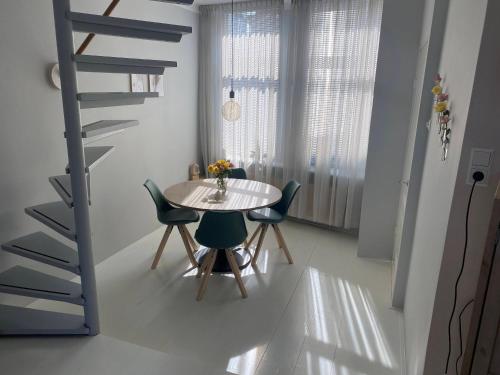 ein Esszimmer mit einem Tisch, Stühlen und einer Treppe in der Unterkunft Het Popelhuisje in Alkmaar