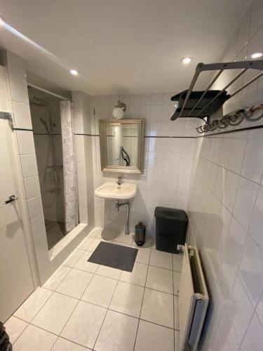 een witte badkamer met een wastafel en een spiegel bij Het Popelhuisje in Alkmaar