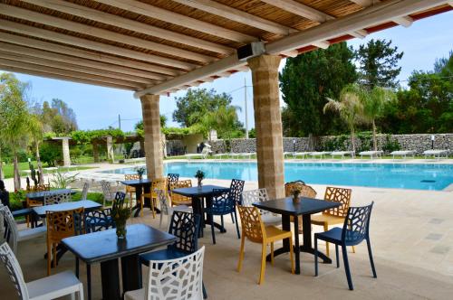 un patio con mesas y sillas junto a una piscina en Agriturismo Masseria del Bosco Makyva, en Borgagne