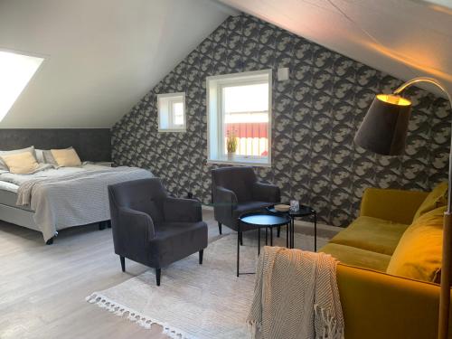 een slaapkamer met een bed en een bank en stoelen bij Hamnhuset Björkö in Björkö