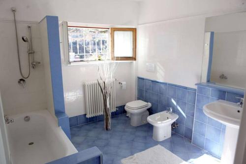 a blue and white bathroom with a toilet and a sink at Villa San Sisinnio Argegno in Argegno