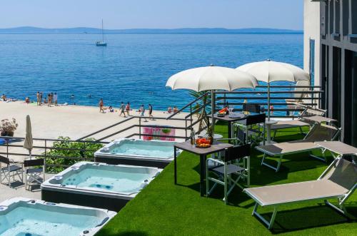 a patio with tables and umbrellas next to the beach at Via Mare Luxury Rooms in Split