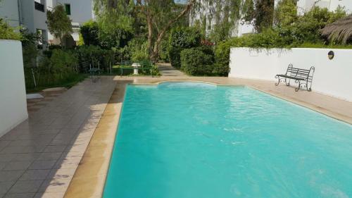 a blue swimming pool with a bench next to a building at Appartement de charme in Nabeul