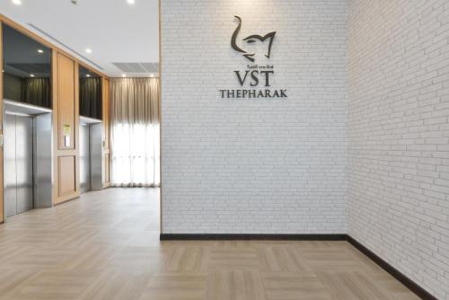 a hallway with a white brick wall and a sign on a wall at VST Residence -SHA PLUS Certified in Ban Khlong Bang Ping