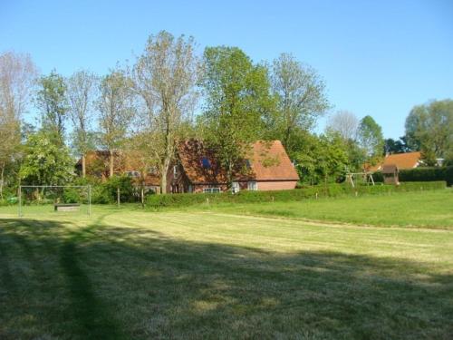 un gran campo de césped con una casa en el fondo en Münchhausen EG en Wangerland