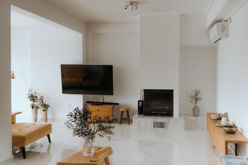 een woonkamer met een flatscreen-tv aan een witte muur bij Greek Sea Villas Kaki Thalassa 400 meters to the beach in Keratea