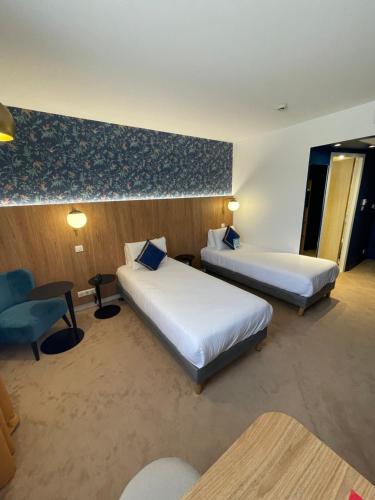 a hotel room with two beds and a chair at Kyriad Aix Les Milles - Plan de Campagne in Bouc-Bel-Air
