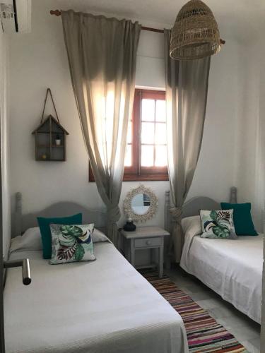 ein Schlafzimmer mit zwei Betten und einem Fenster mit Vorhängen in der Unterkunft CM - Campomar Mojacar in Mojácar