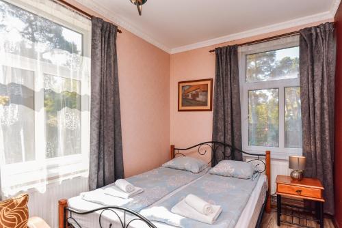 a bedroom with a bed and two windows at Villa Victoria in Ventspils
