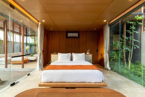 Ce lit se trouve dans un dortoir doté de murs en verre. dans l'établissement Rumah Amadangi, à Tanah Lot