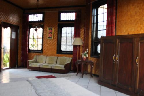 a bedroom with a bed and a couch and windows at Puri Agung Inn in Sidemen