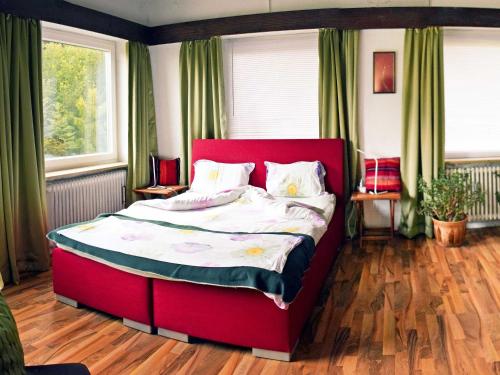 a red bed in a bedroom with green curtains at Kandelbleibe in Waldkirch