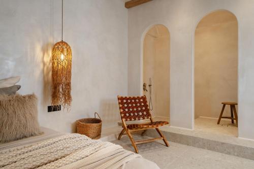 a bedroom with a bed and a chair and a chandelier at Stoa Suites in Naxos Chora
